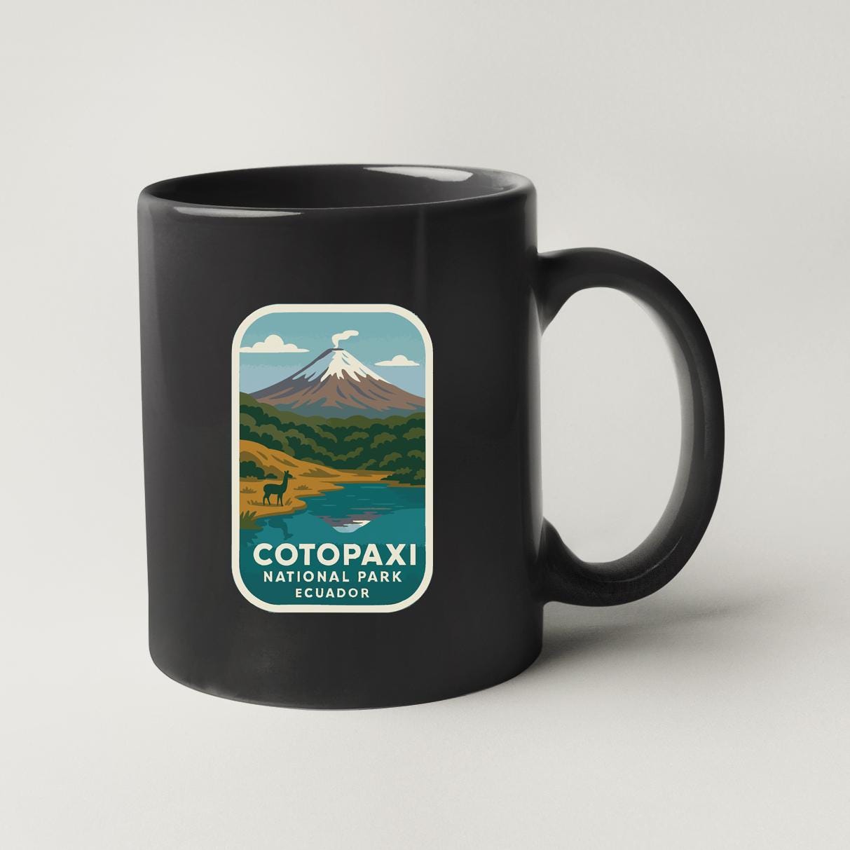 A black coffee mug with a label that says "COTOPAXI NATIONAL PARK SCUBA" and features an illustration of a mountain landscape with a lake and a llama.
