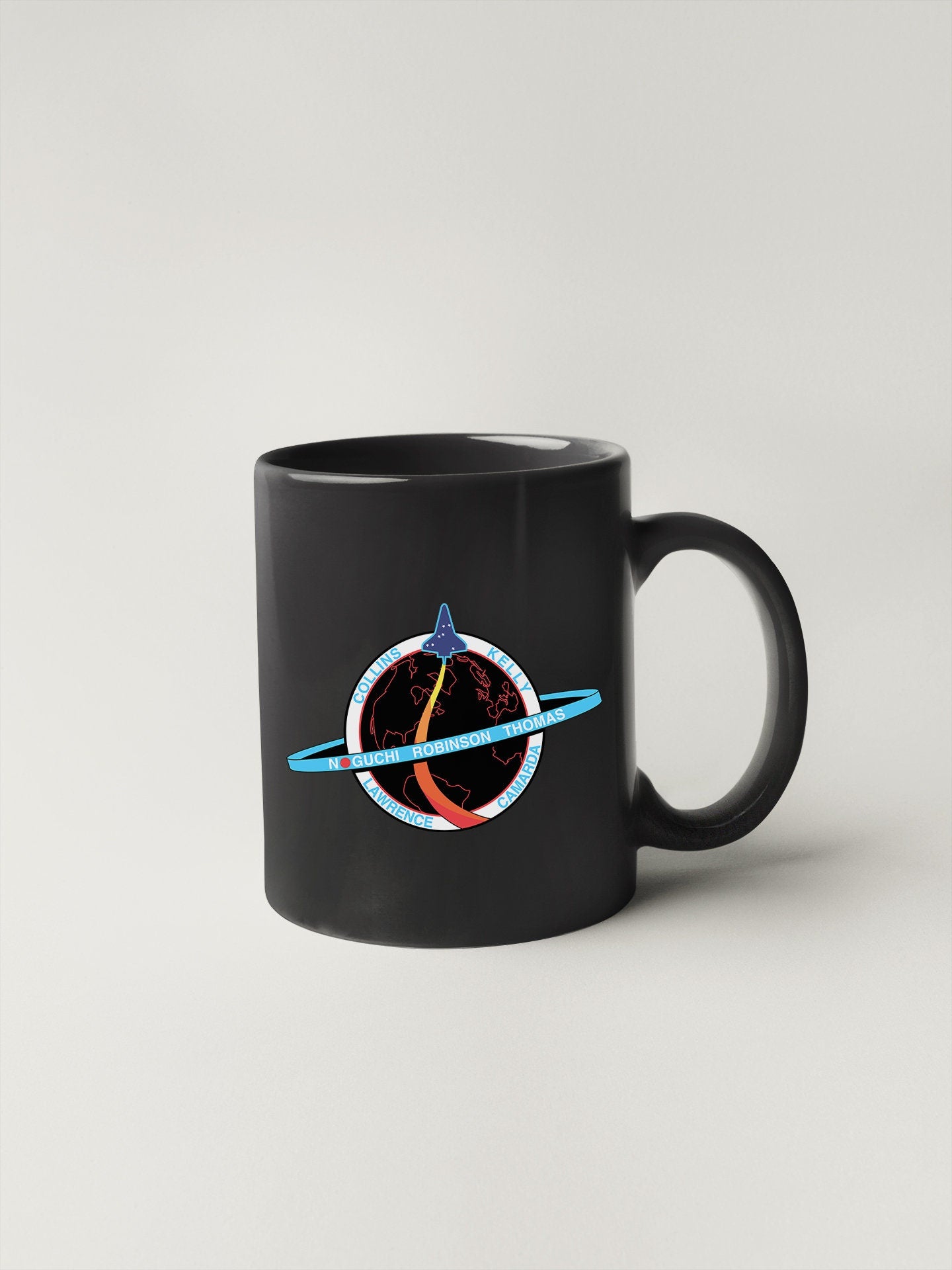 a black coffee mug with a picture of saturn on it
