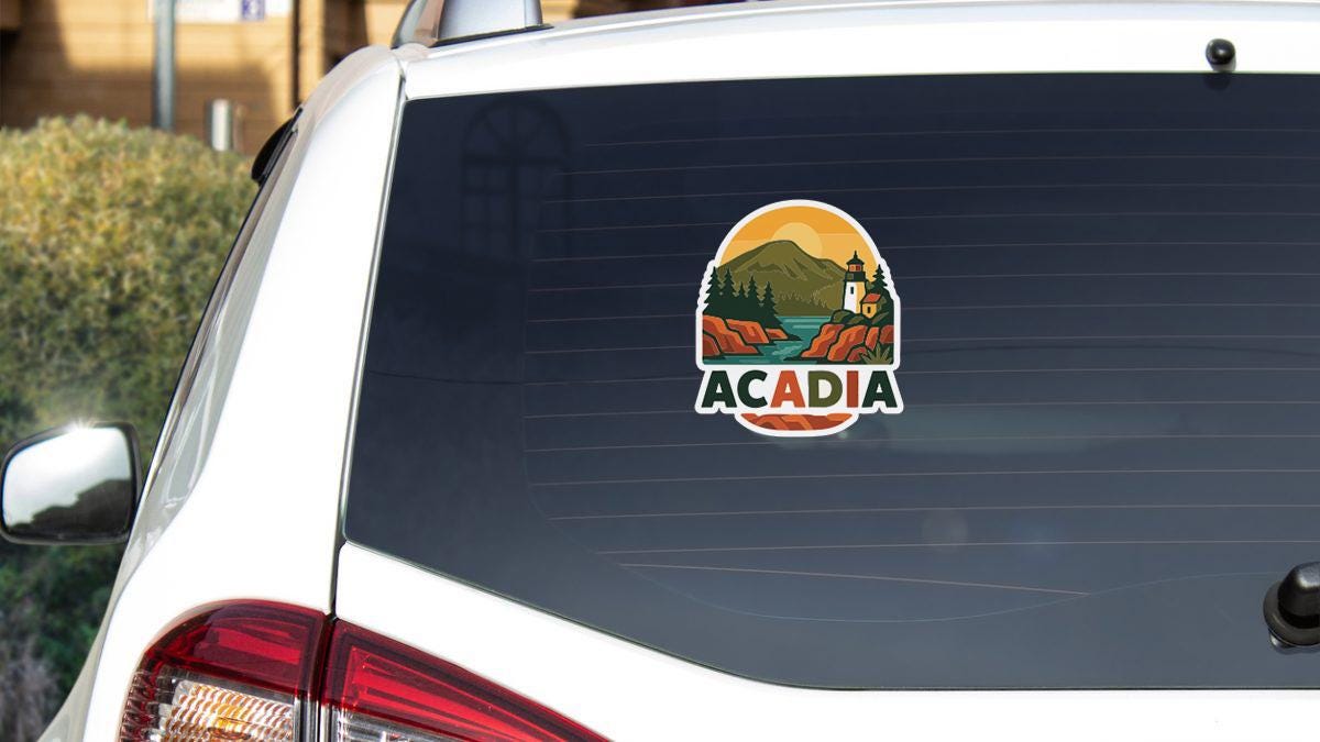 A sticker on the rear window of a white vehicle that says "ACADIA".