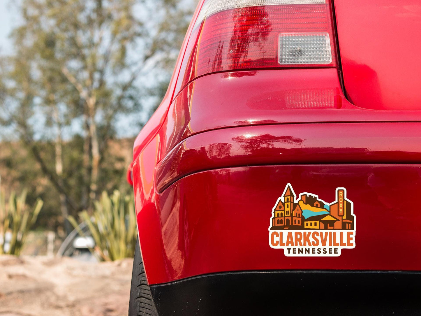 the rear end of a red car with a sticker on the trunk that says "CLARKSVILLE TENNESSEE".