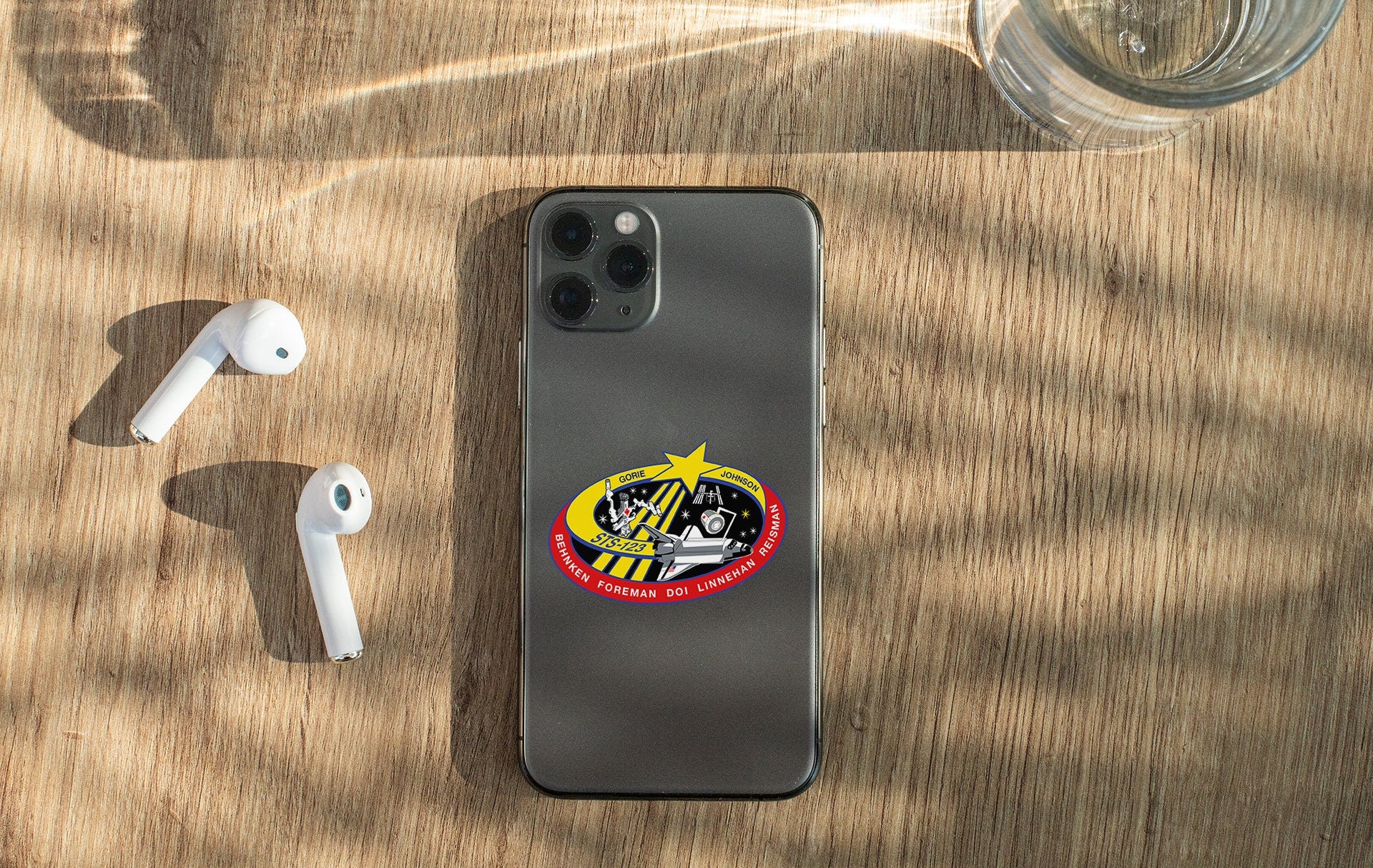 a phone with a sticker on it next to ear buds