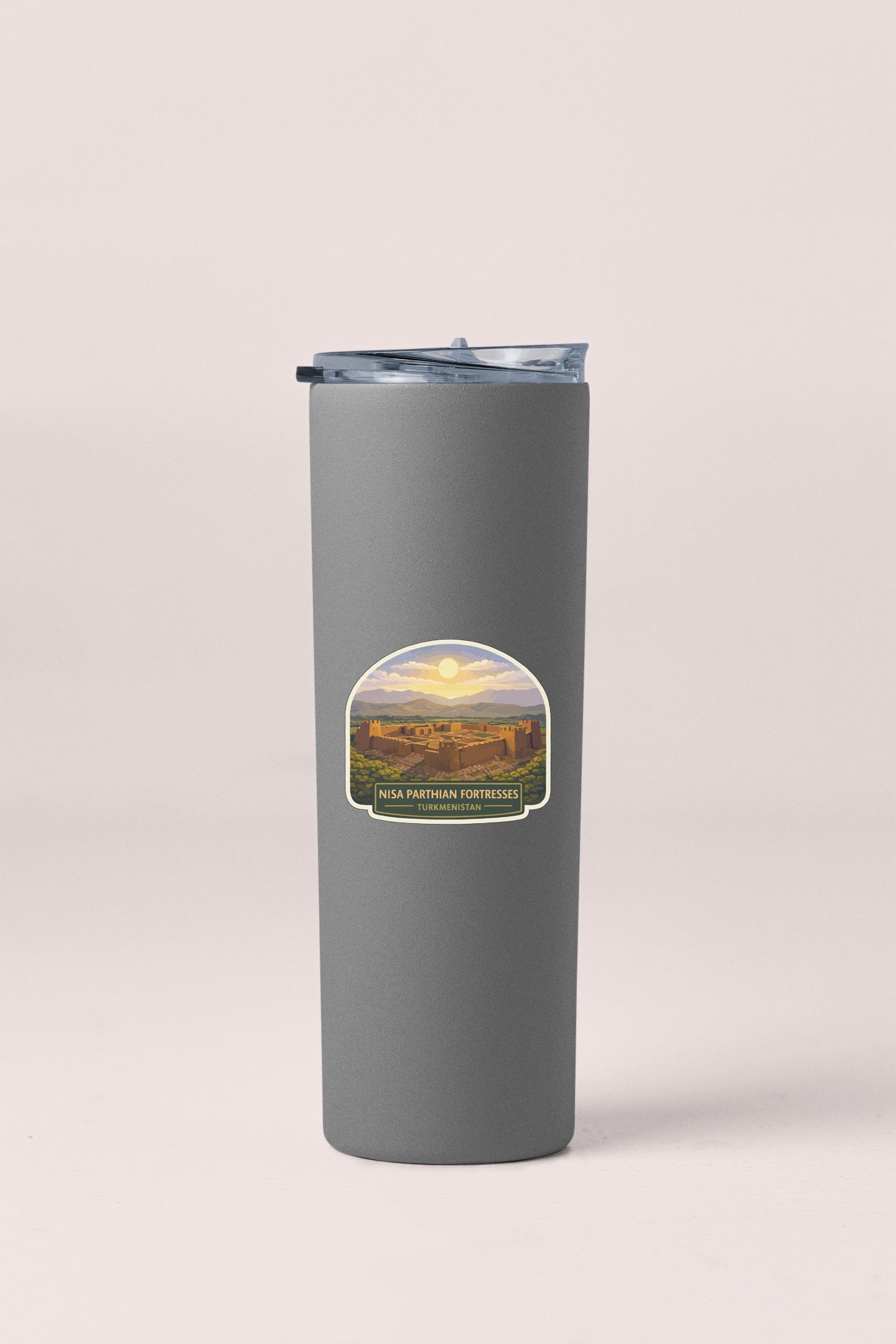 A gray insulated tumbler with a lid and a label featuring a desert landscape with a sunset.