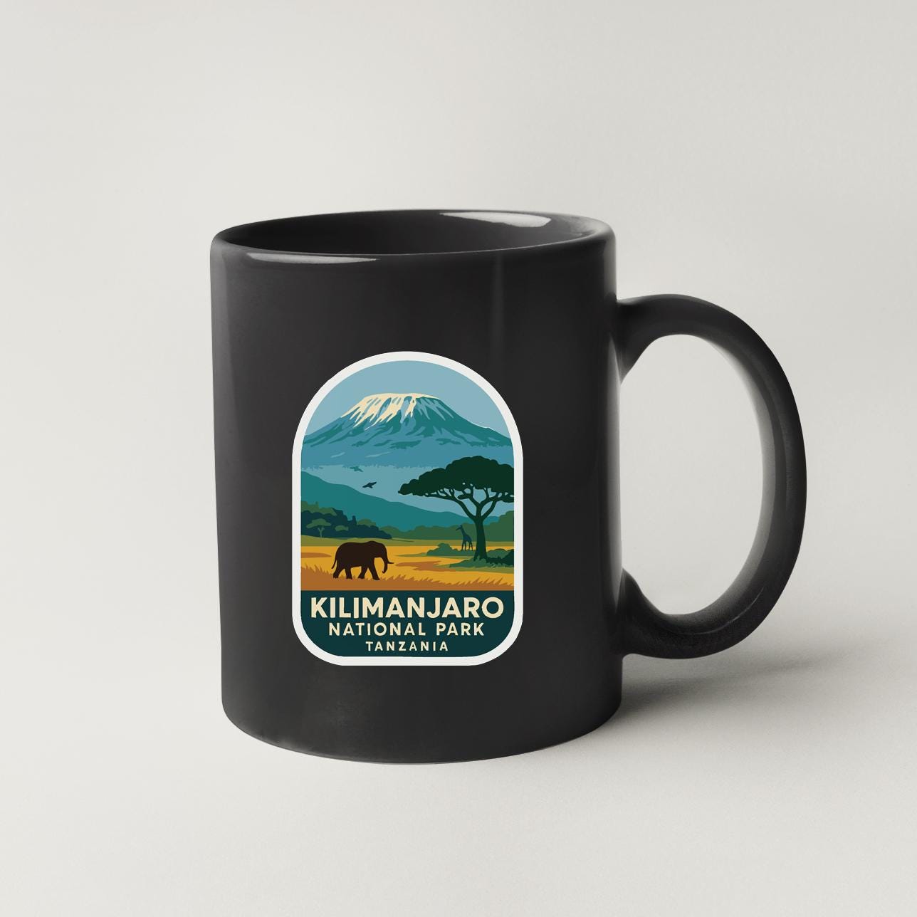 A black coffee mug with a label that says "Kilimanjaro National Park Tanzania".
