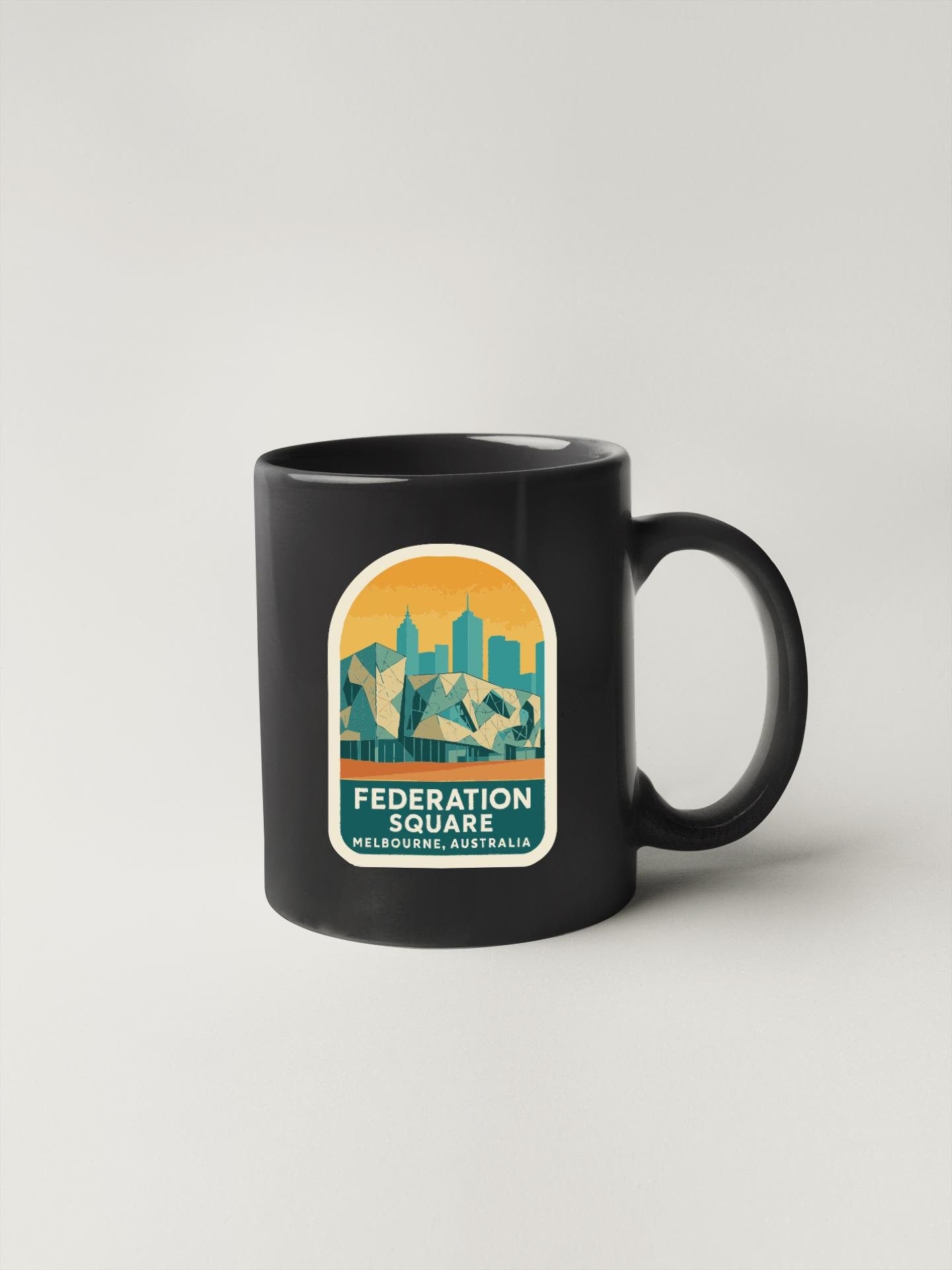 A black coffee mug with a graphic design featuring a city skyline and the text "FEDERATION SQUARE MELBOURNE, AUSTRALIA".