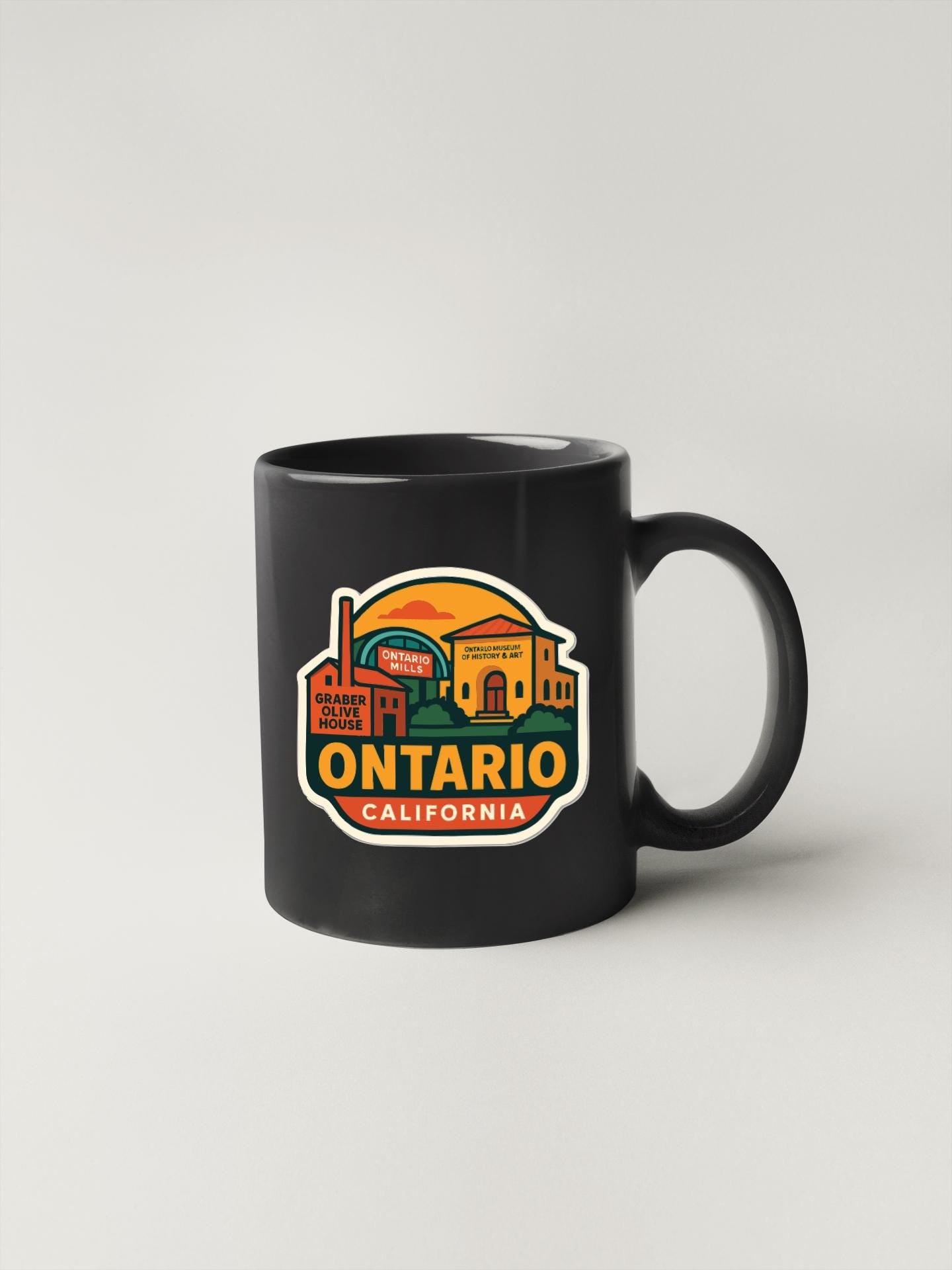 A black coffee mug with a colorful graphic design depicting a cityscape and the text "ONTARIO CALIFORNIA".