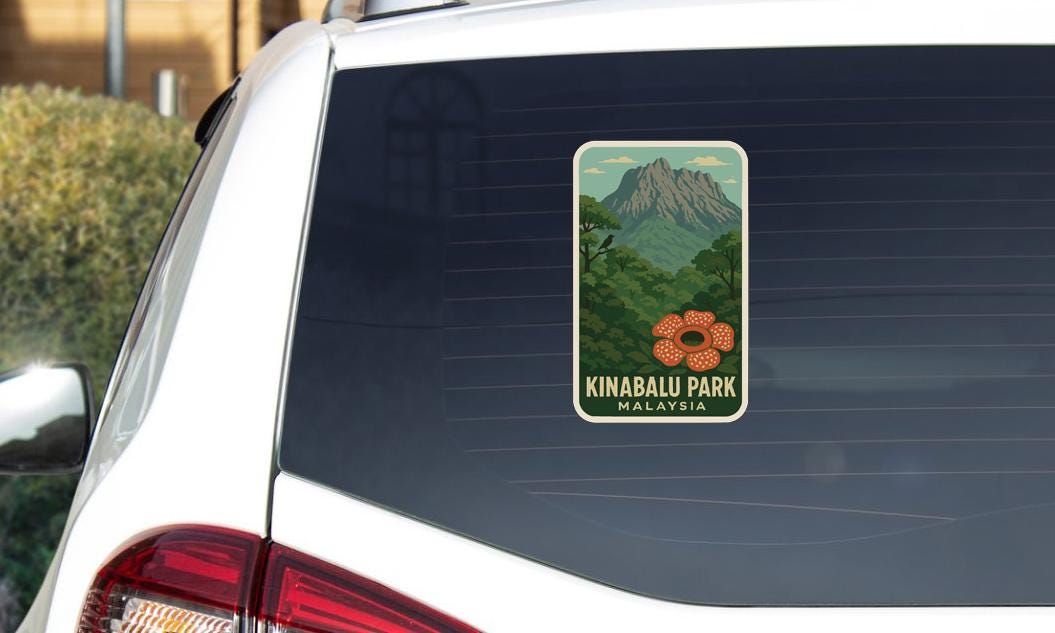 A sticker on the rear window of a car, depicting a mountain landscape with a flower in the foreground.