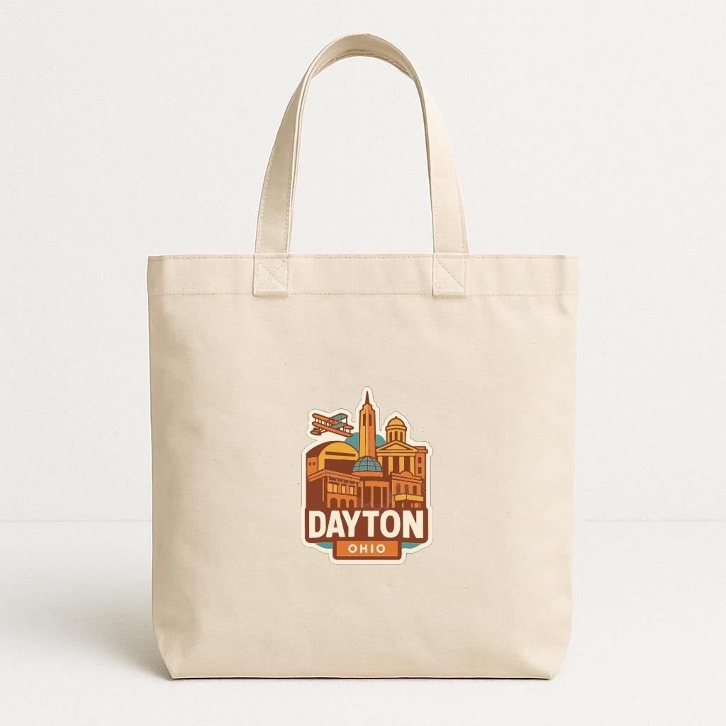 A beige tote bag with a graphic of the Dayton, Ohio skyline printed on it.