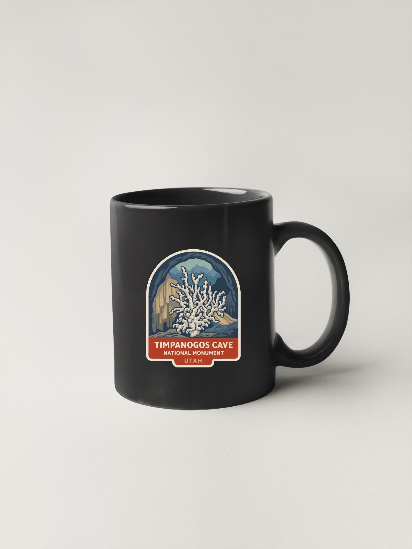 A black coffee mug with a label that says "Timpanogos Cave National Monument" and features an illustration of the cave.