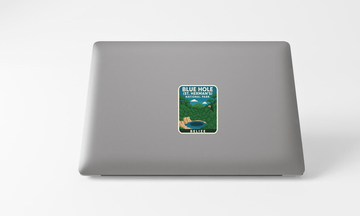 A sticker on the back of a laptop, depicting a scenic landscape with mountains, a lake, and a blue sky.