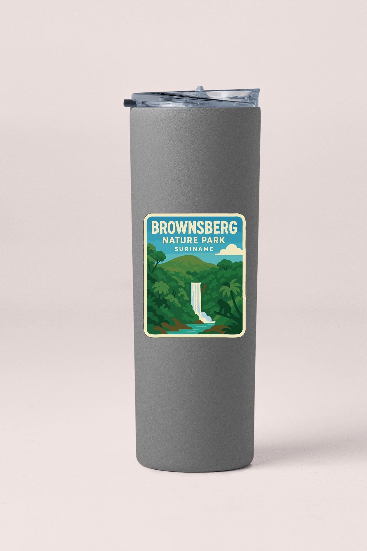 A gray insulated tumbler with a label that reads "Brownsberg Nature Park Subirinyam" depicting a waterfall surrounded by lush greenery.