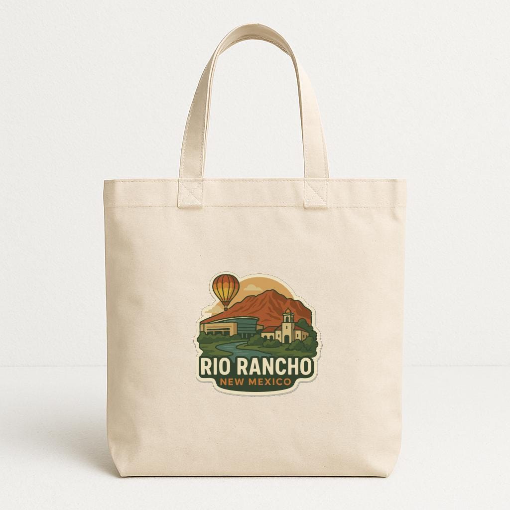 A beige tote bag with a printed design depicting a scenic landscape with mountains, buildings, and a hot air balloon.