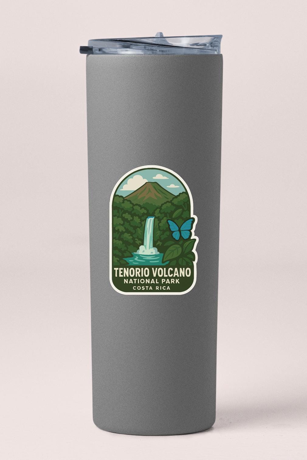 A gray cylindrical container with a label that features an illustration of a waterfall, mountains, and a butterfly.