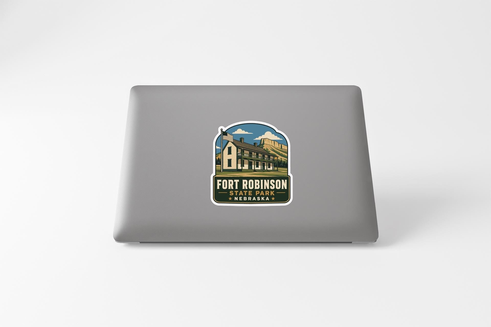 A sticker on the back of a laptop, depicting a building with a blue sky and clouds in the background.