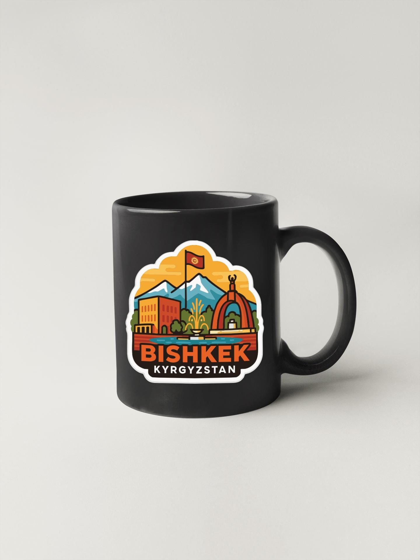 A black coffee mug with a colorful sticker depicting a cityscape and the text "Bishkek Kyrgyzstan" printed on it.