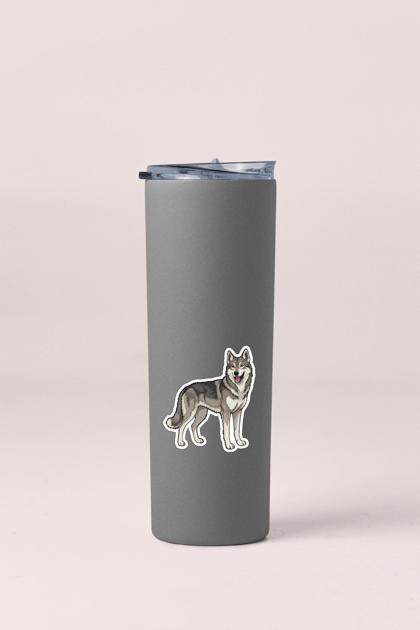 A gray insulated tumbler with a sticker of a wolf on it.