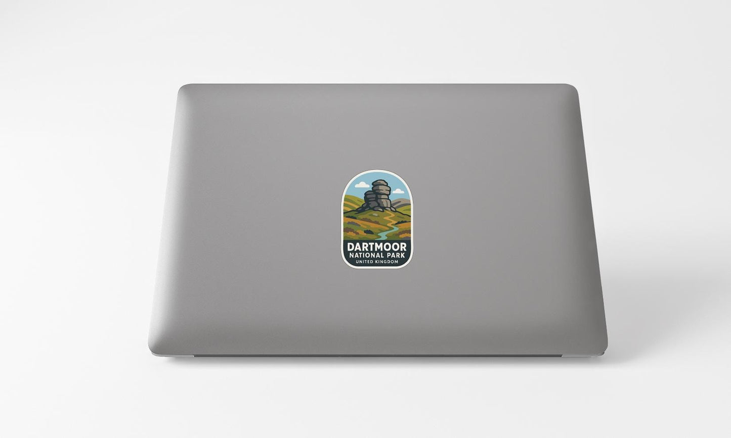 A sticker on the back of a laptop, depicting a scenic landscape with mountains and a castle.