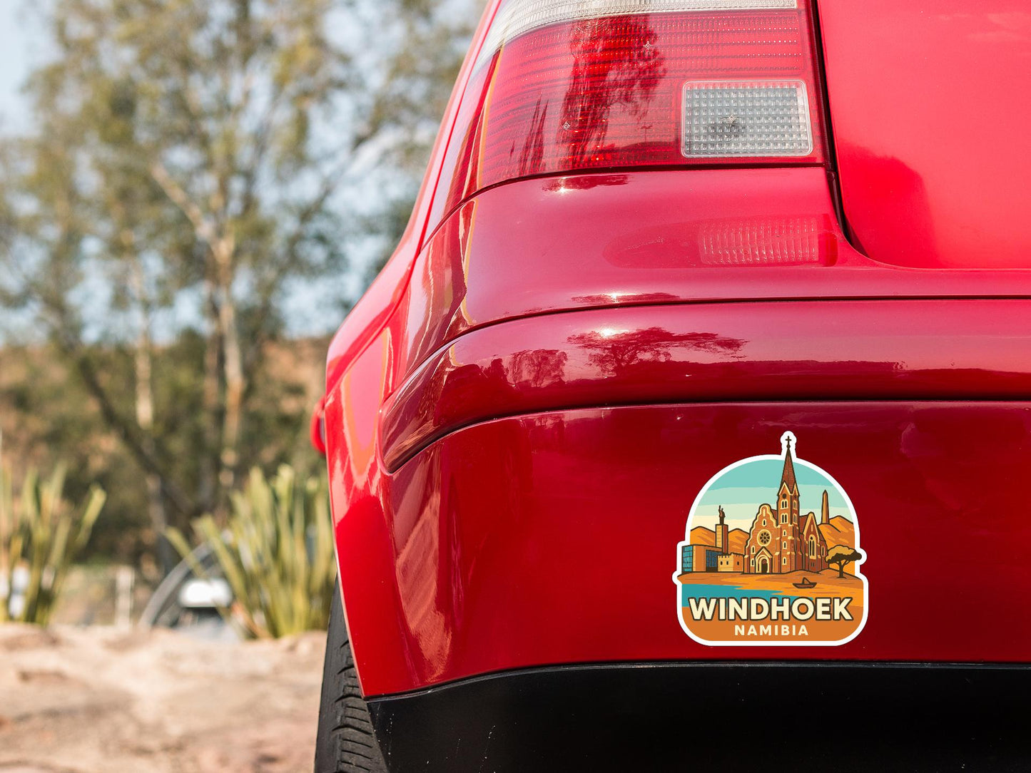 the rear end of a red car with a sticker on the trunk that says "WINDHOEK NAMIBIA".