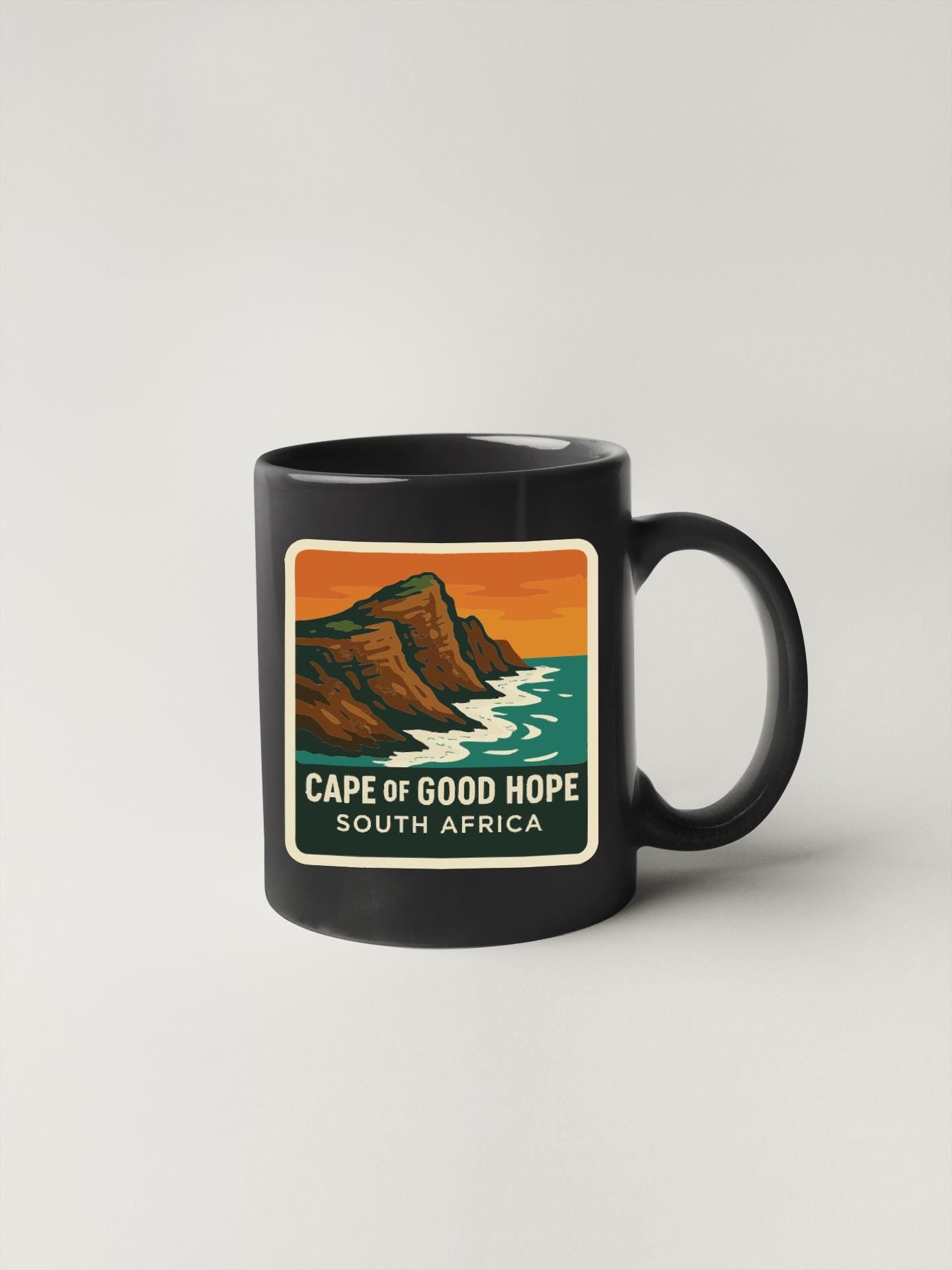 A black coffee mug with a graphic design depicting the Cape of Good Hope, a famous landmark in South Africa.