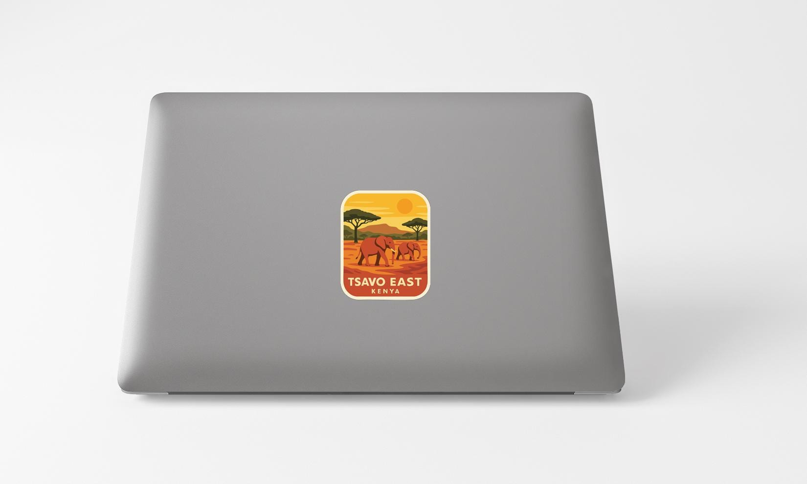 A sticker on the back of a laptop displaying an illustration of elephants in a savanna landscape with the text "TSAVO EAST KENYA".