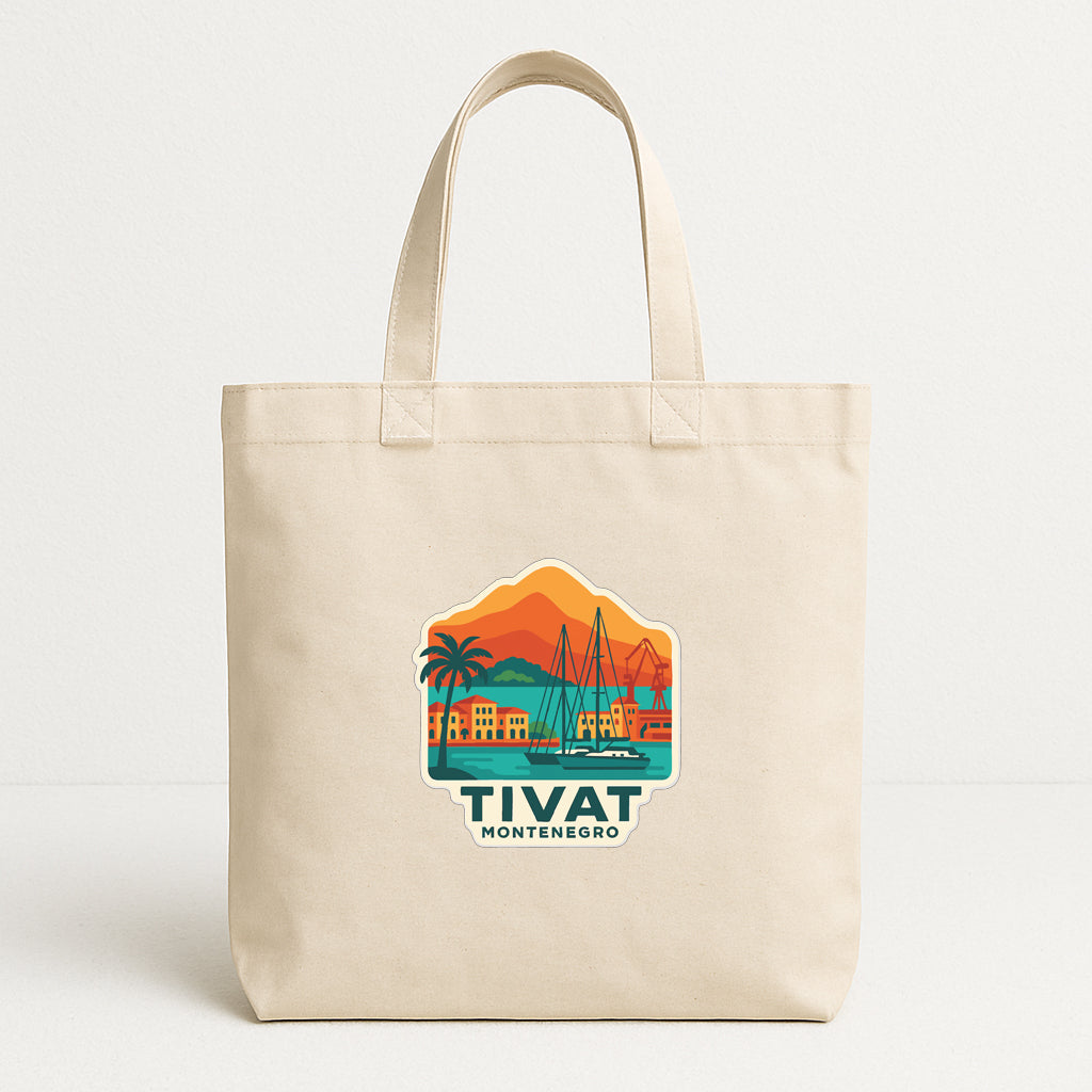 A beige tote bag with a graphic design depicting a coastal town scene, including a palm tree, buildings, and mountains.