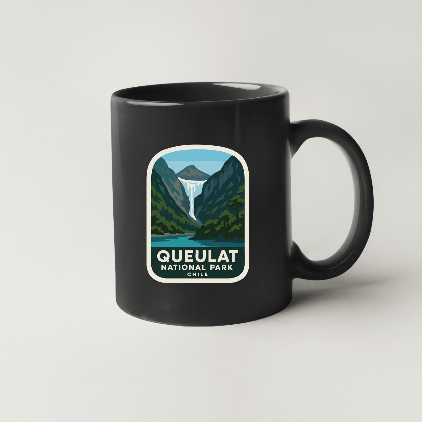 A black coffee mug with a graphic design depictingqueulat national park in Chile.