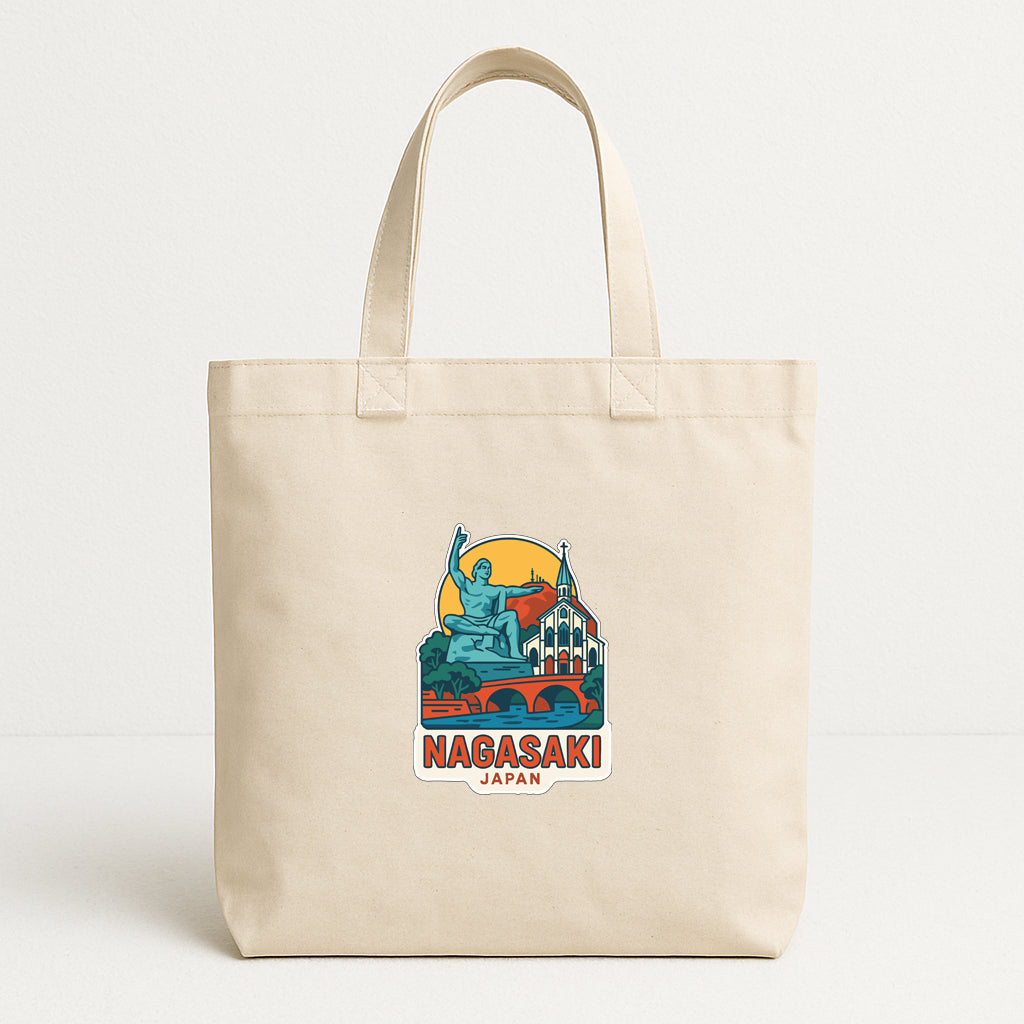 A beige tote bag with a graphic design featuring a statue and a cityscape, along with the text "Nagaski Japan".