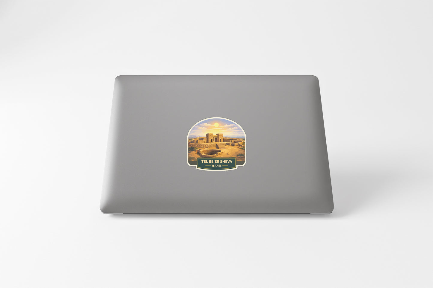 a sticker on the back of a laptop, depicting a desert cityscape with a prominent tower in the center.
