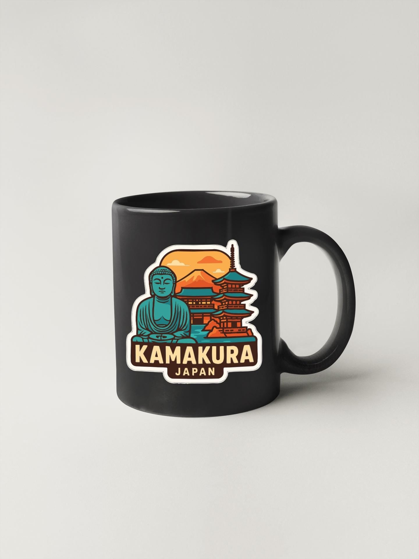 A black coffee mug with a colorful illustration of a temple and a Buddha statue, along with the text "KAMAKURA JAPAN".