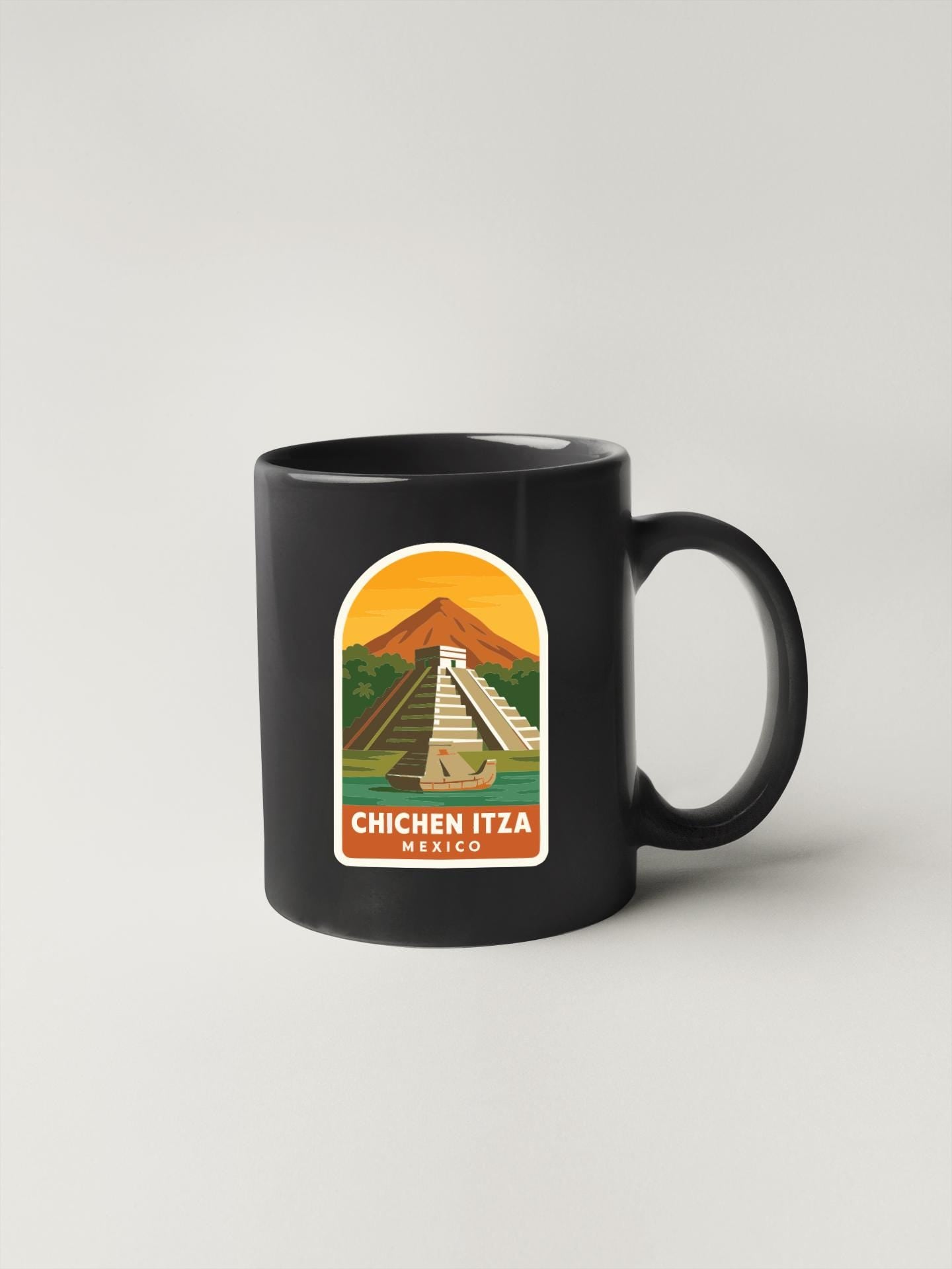 A black coffee mug with a sticker depicting the Mayan ruins of Chichen Itza in Mexico.
