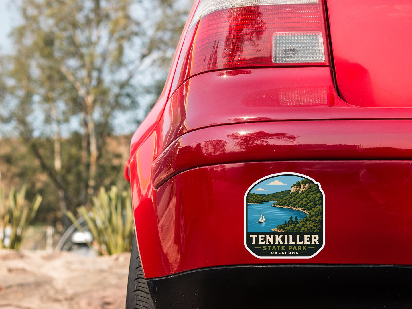 the rear end of a red car with a sticker on the back window that says "TENKILLER STATE PARK OLLAMOND".