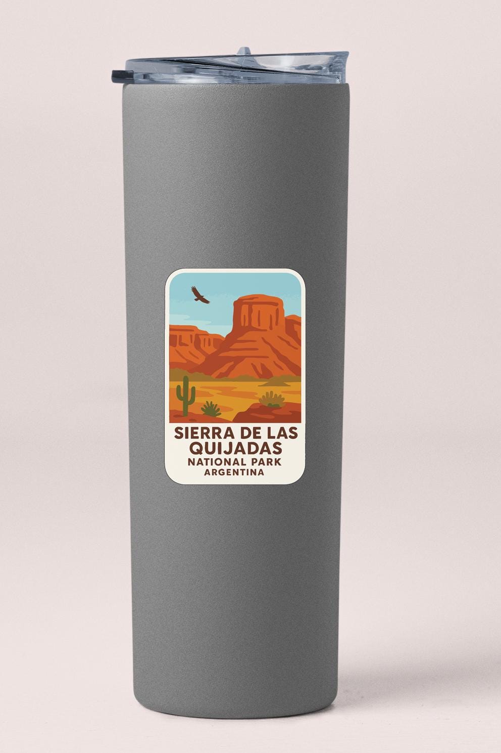 A gray insulated tumbler with a label that features an illustration of the Sierra de Las Guijadas National Park in Argentina.