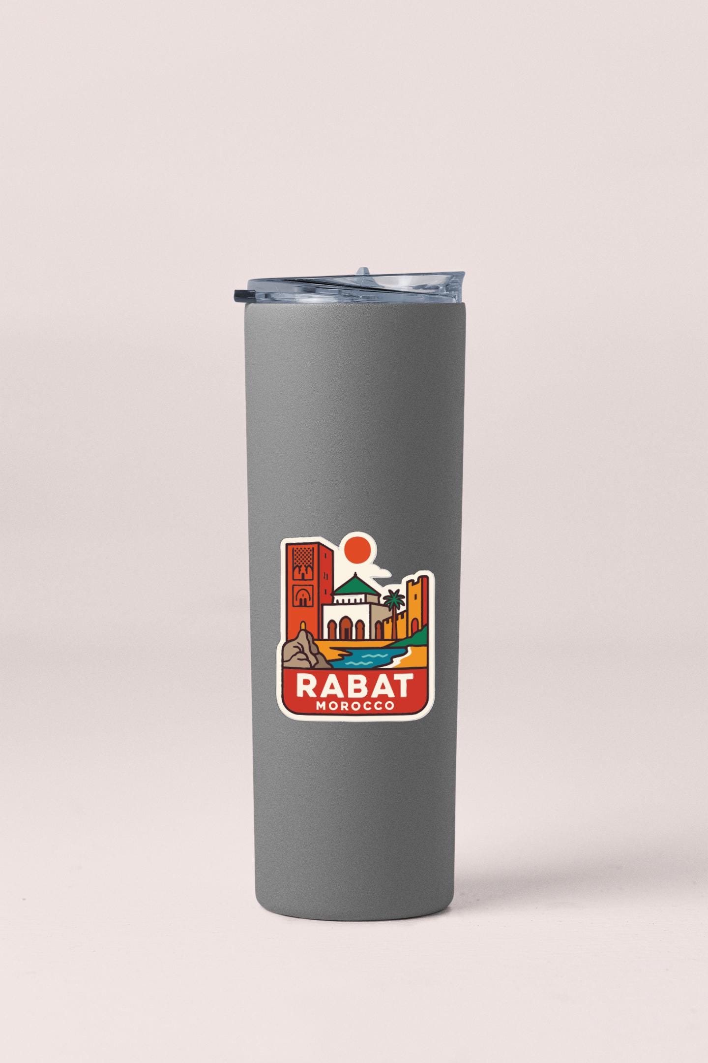 A gray insulated tumbler with a sticker featuring an illustration of Rabat, Morocco.