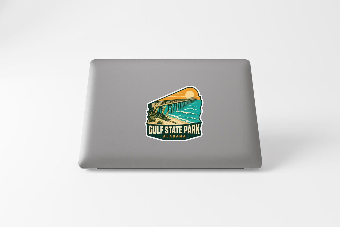 A sticker on the back of a laptop, depicting a scenic view of Gulf State Park in Alabama.