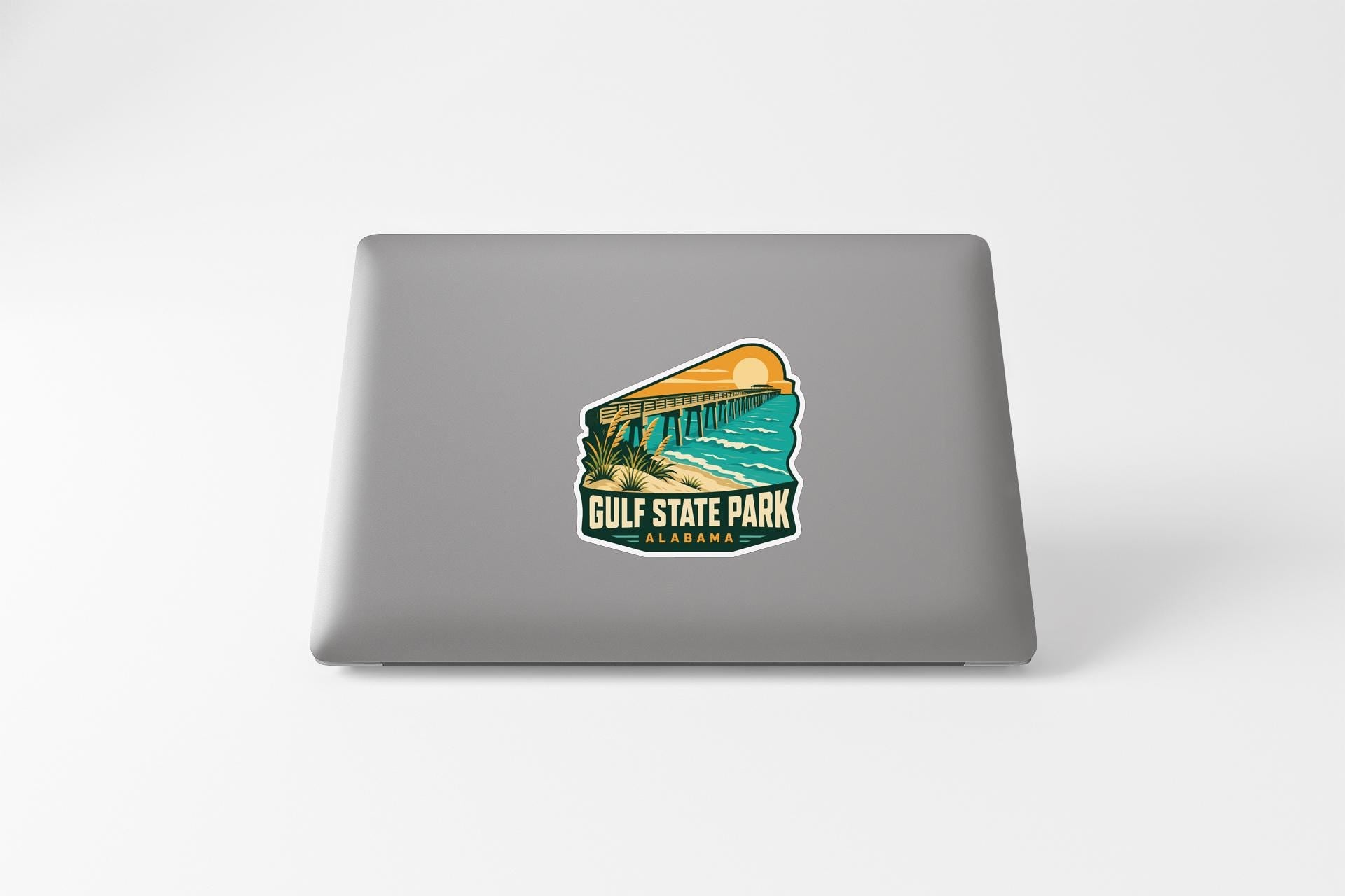 A sticker on the back of a laptop, depicting a scenic view of Gulf State Park in Alabama.