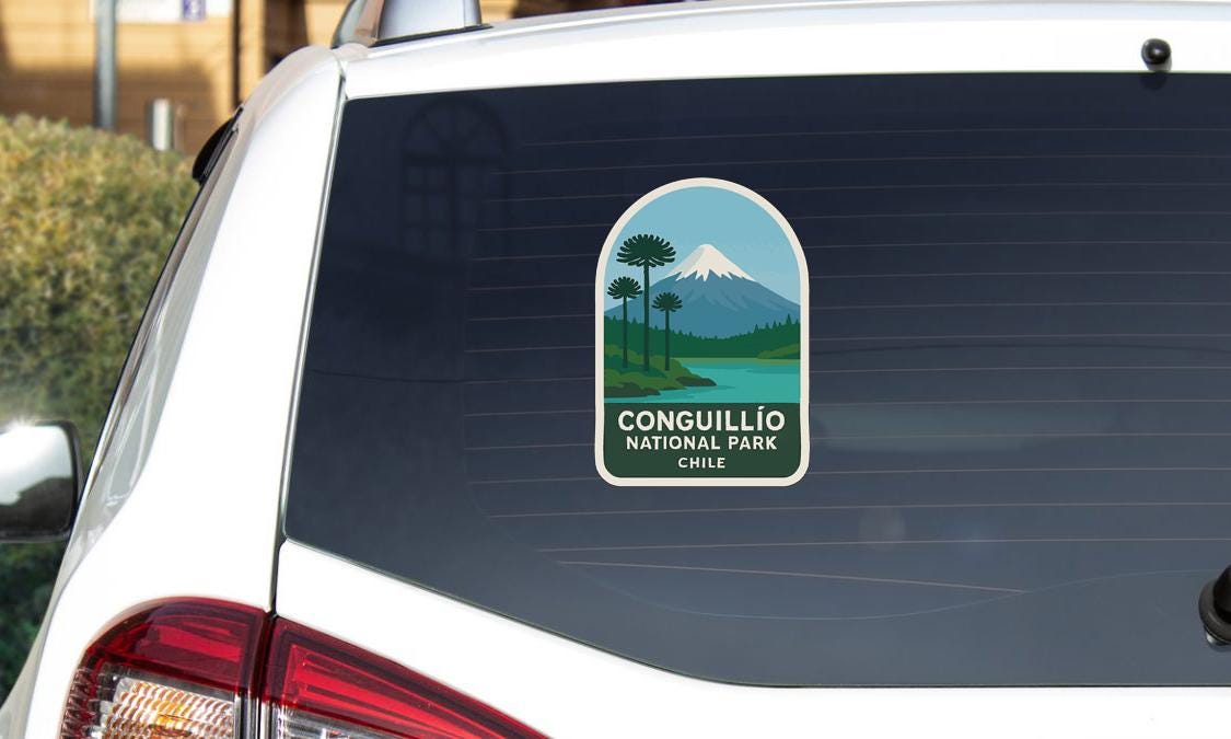 a sticker on the rear window of a white car, depicting a scenic landscape with a mountain and palm trees.