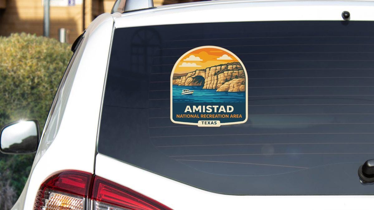 a sticker on the rear window of a white vehicle, depicting a scenic landscape with a boat on the water and a cliff in the background.