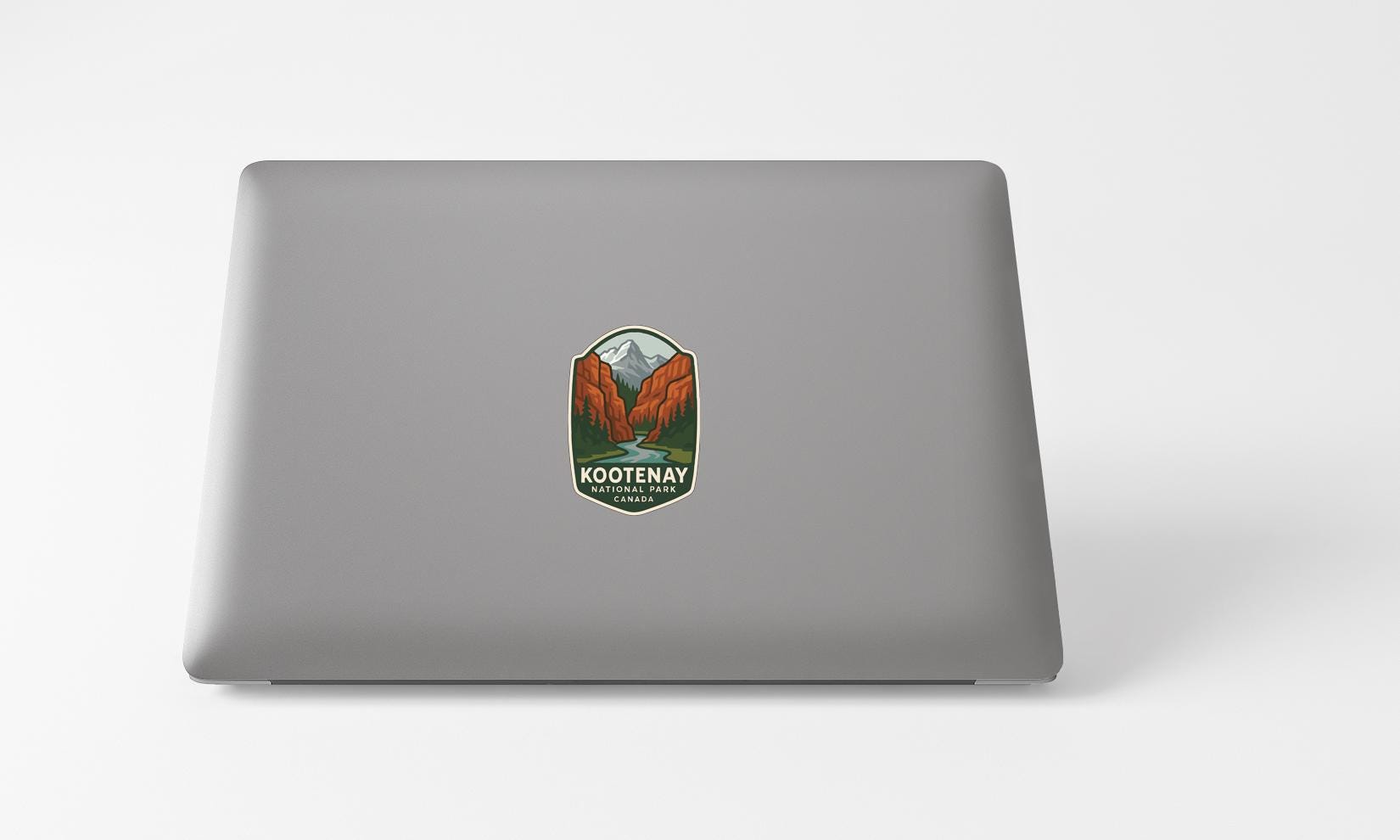 A sticker with a mountain landscape and the text "Kotenay National Park" printed on a laptop.