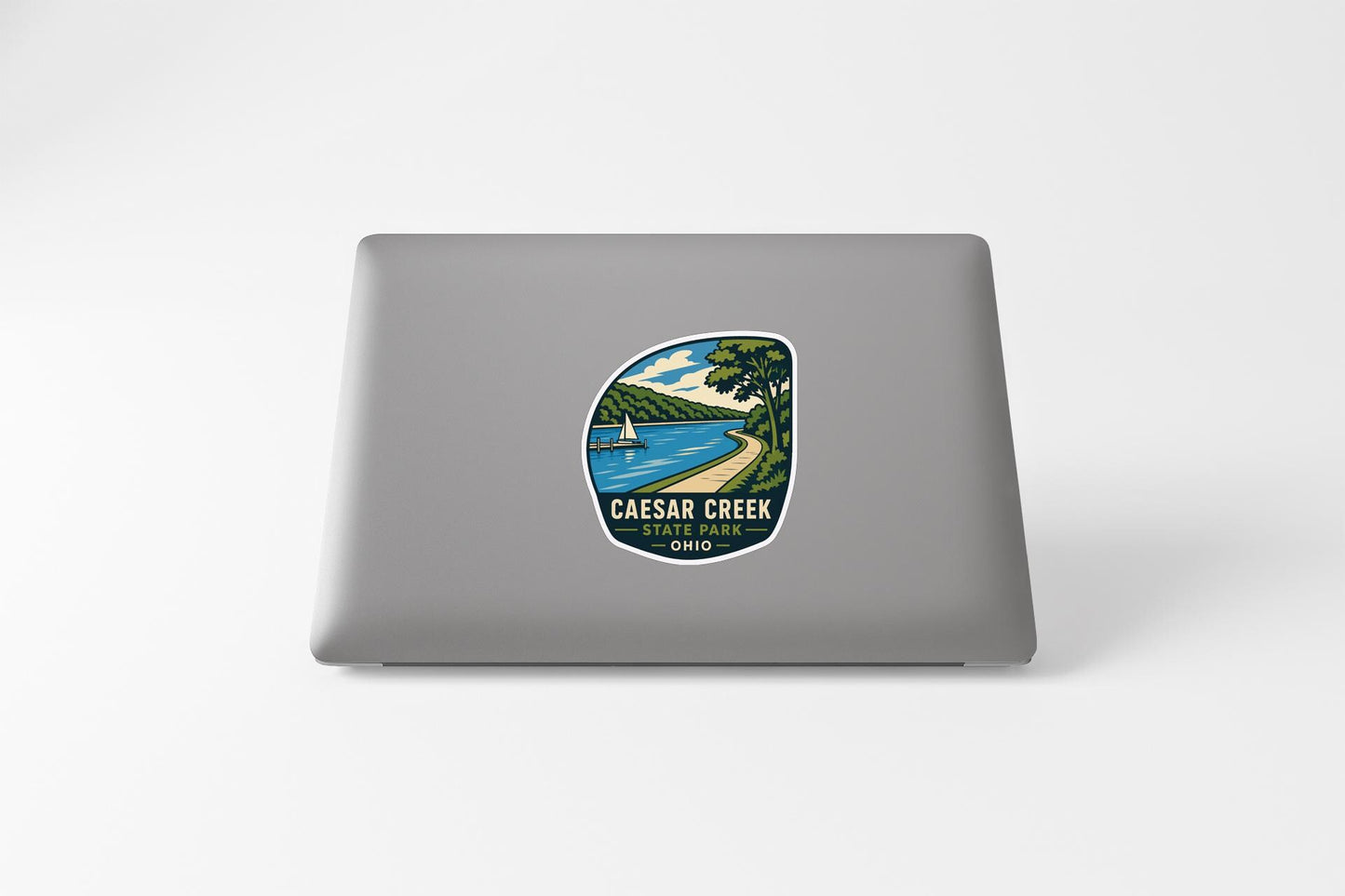a sticker on the back of a laptop that depicts a scenic view of Caesar Creek in Ohio.