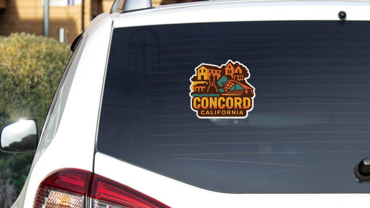 the rear window of a white car with a sticker on it, featuring a colorful illustration of a town or city.
