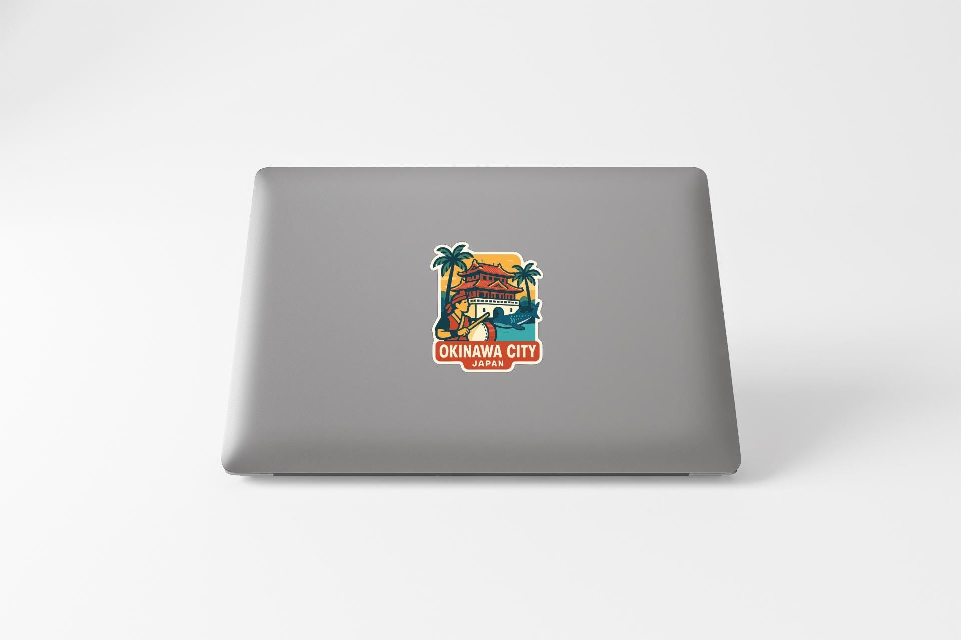 a sticker on the back of a laptop that says "OKINAWA CITY JAPAN".