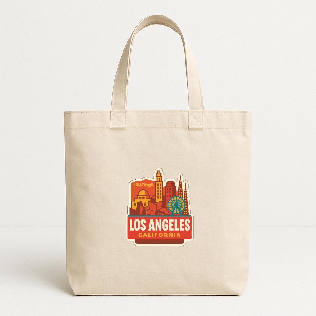 A beige tote bag with a printed design of the Los Angeles skyline and the text "LOS ANGELES, CALIFORNIA" printed on it.