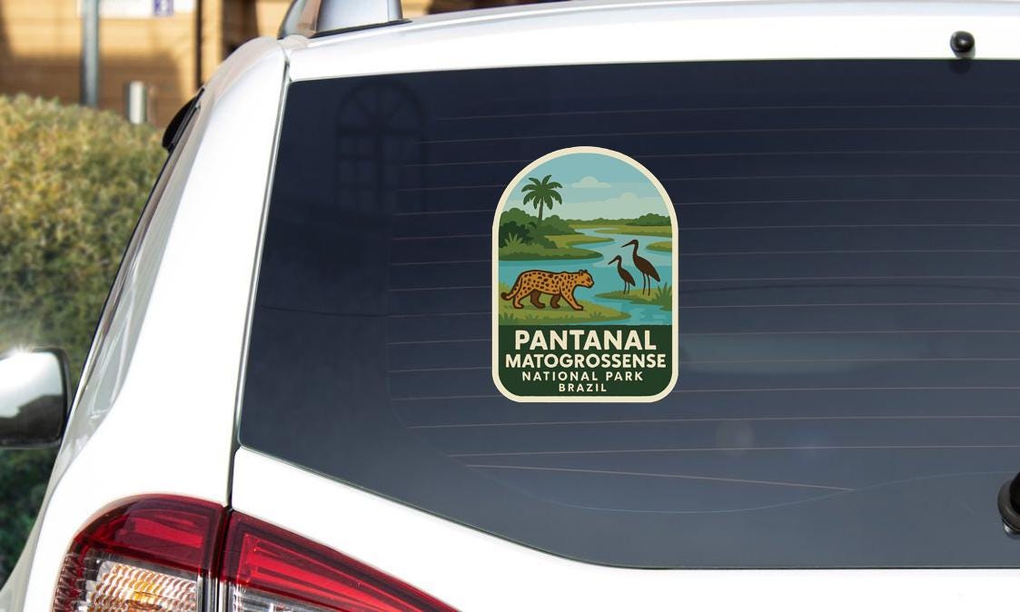 A sticker on the rear window of a white car, depicting a leopard and a bird, with the text "PANTANAL MATOGROSSENSE NATIONAL PARK BRASIL".