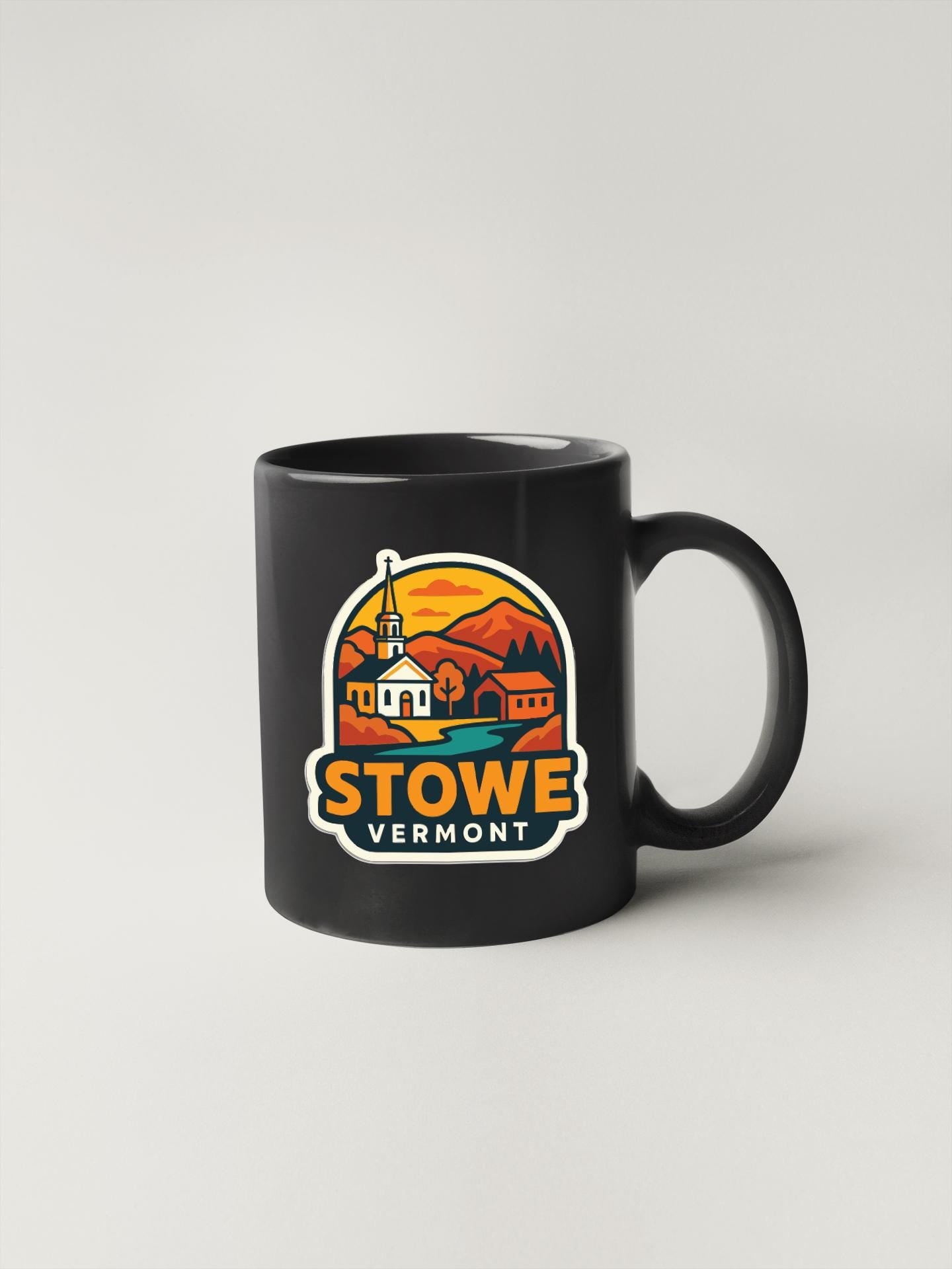 A black coffee mug with a colorful graphic design depicting Stowe, Vermont.