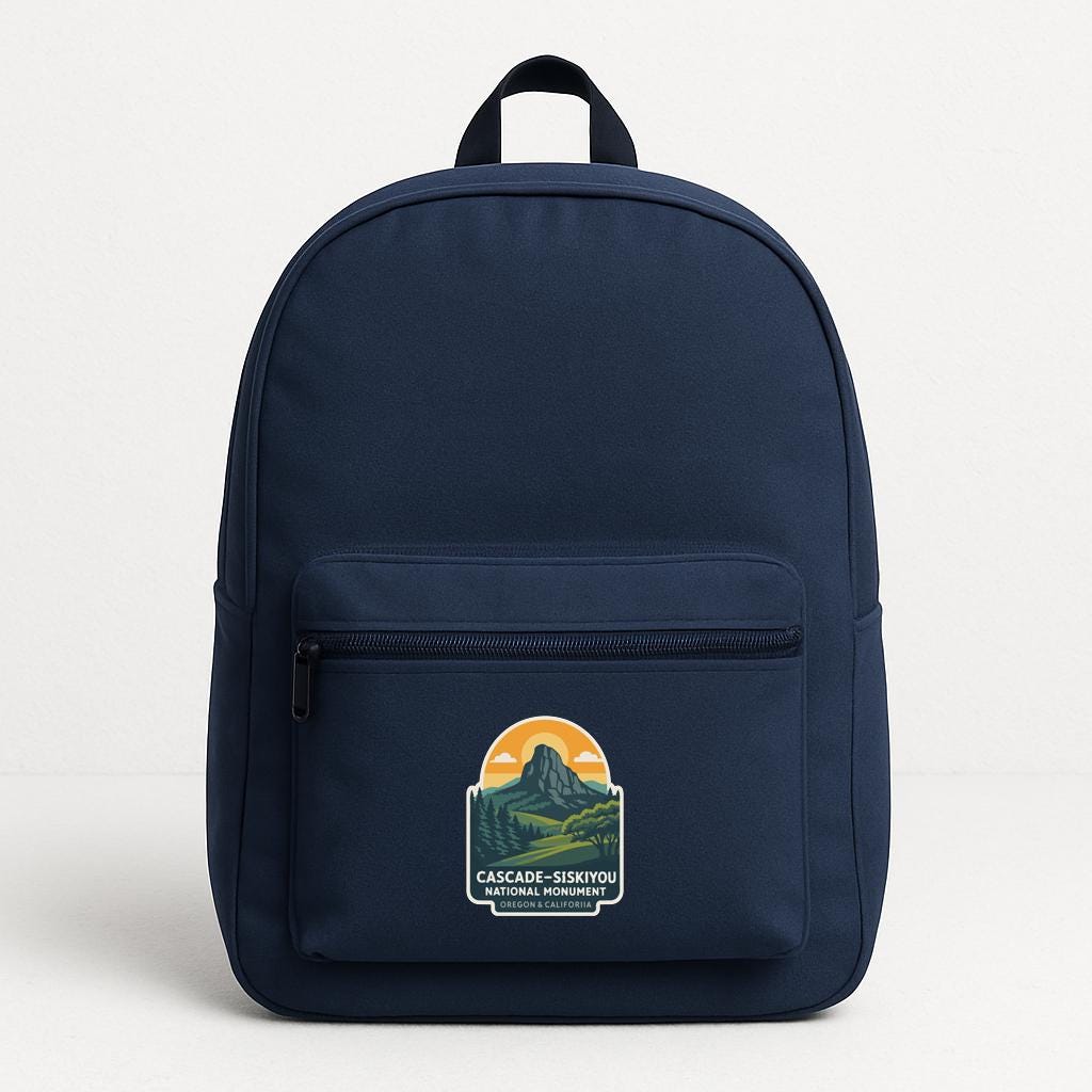 A navy blue backpack with a graphic of a mountain and the text "CASCADIE-SILKYOU NATIONAL ADVENTURE" printed on it.