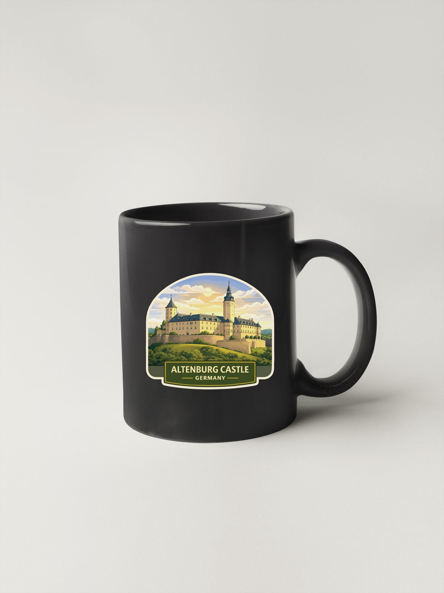 A black coffee mug with a sticker depicting the Altenburg Castle in Germany.