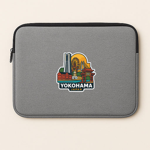 A gray laptop sleeve with a colorful sticker depicting the city of Yokohama, Japan.