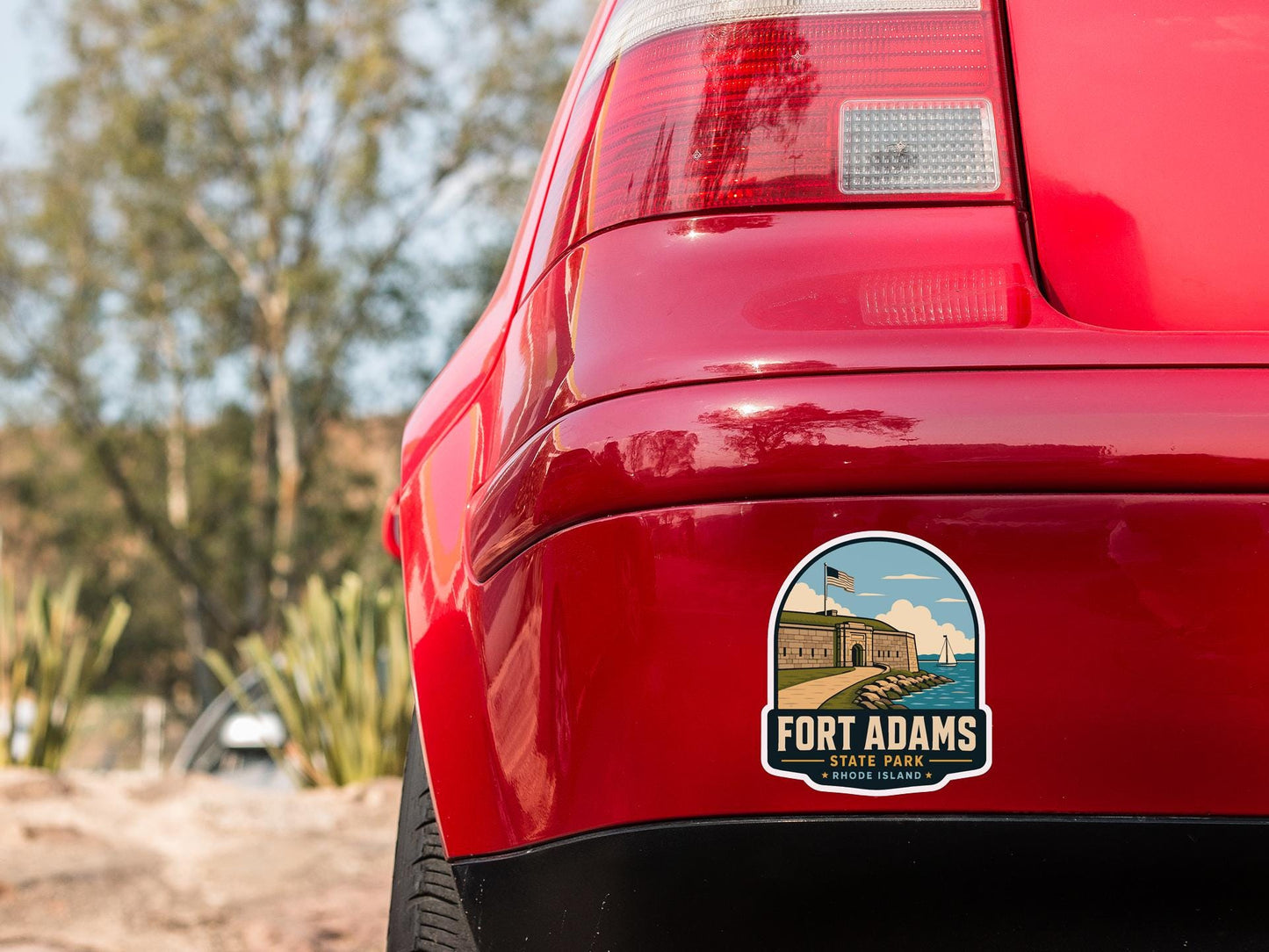 the rear end of a red car with a sticker on the bumper that says "Fort Adams State Park Rhode Island".