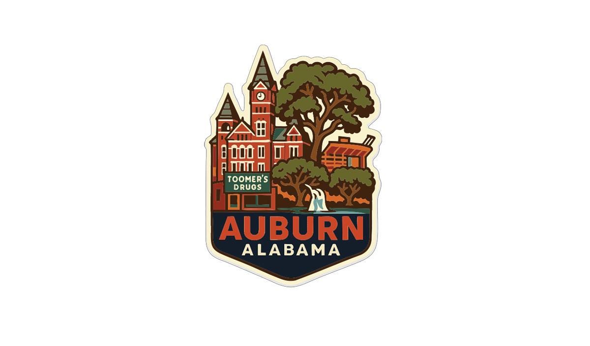 A sticker or emblem featuring a stylized illustration of a building with a clock tower, surrounded by trees and a body of water, with the text "AUBURN ALABAMA" prominently displayed.