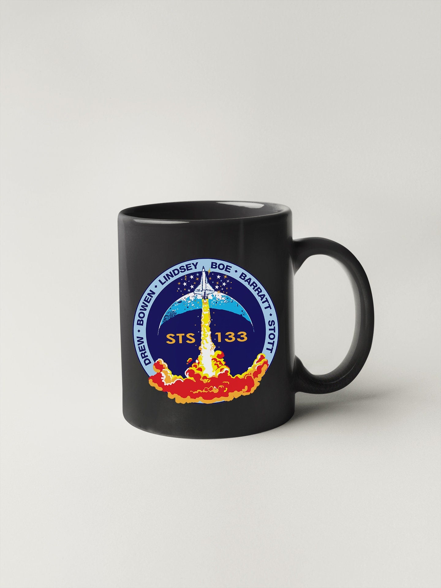 a black coffee mug with a nasa emblem on it