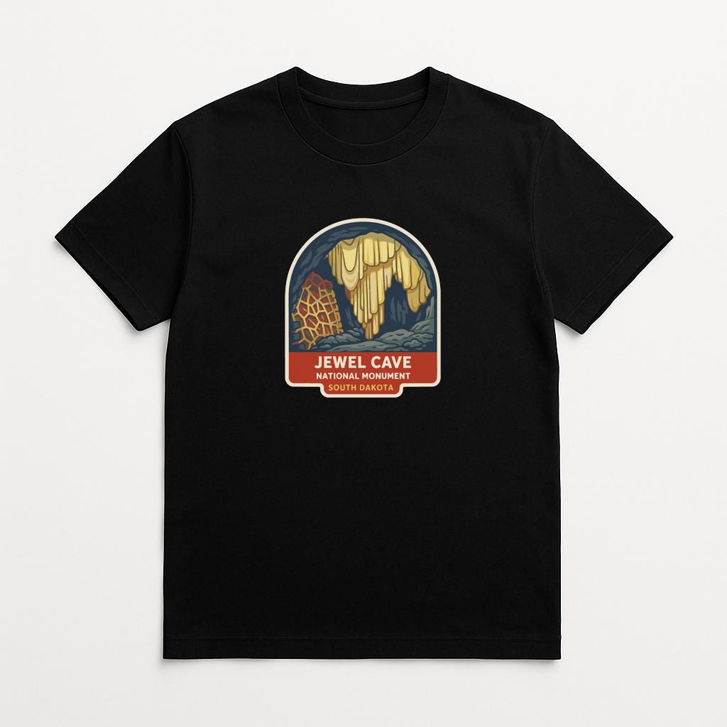 A black t-shirt with a graphic design depicting a cave with a yellow waterfall and a giraffe.